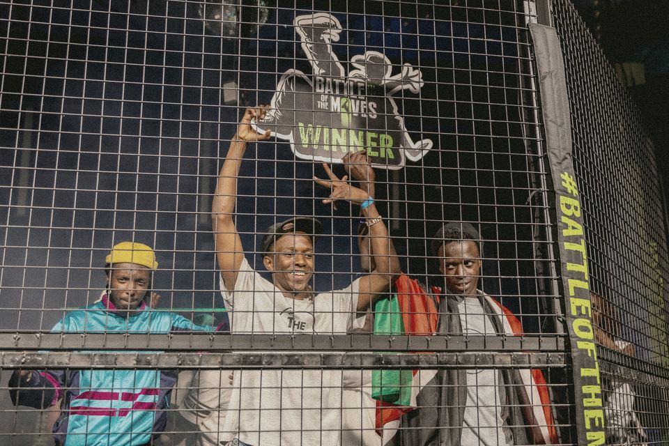 The champion holding the Battle of the Moves winner's trophy up behind the cage.